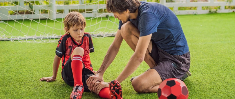little boy and trainer checking knee injury from soccer
