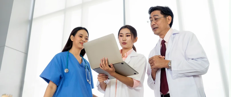 2 doctors and a nurse looking at laptop