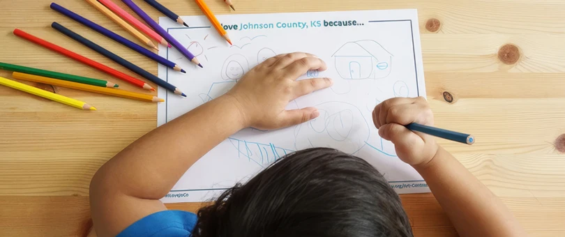 Child drawing on paper with color pencils