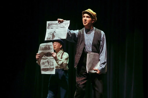 Newsies boy holding newspaper in a play