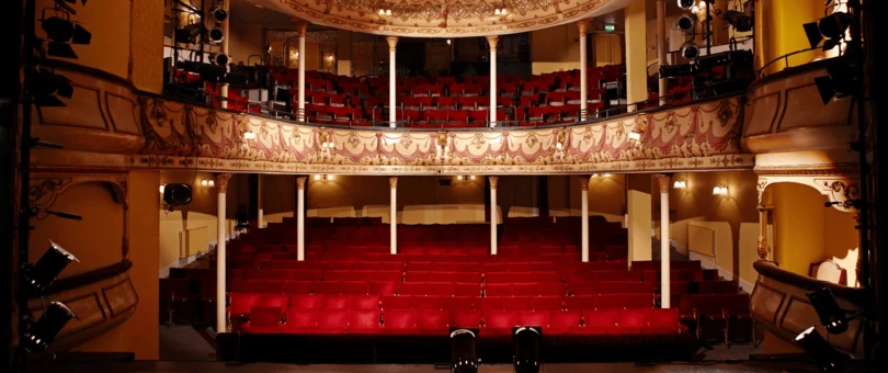ornate theater with three floors, gold trim, and red chairs