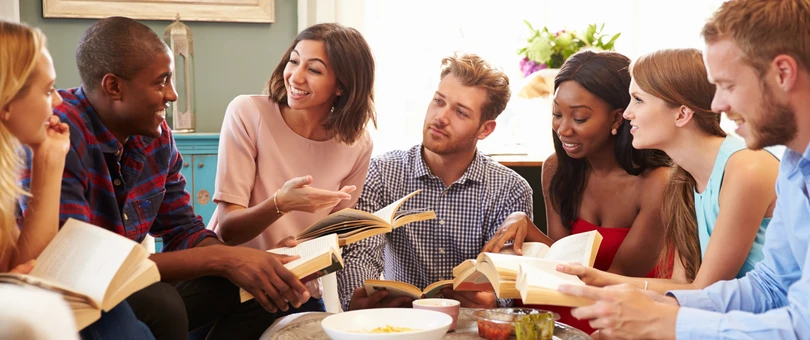 people sitting around a table discussing a book